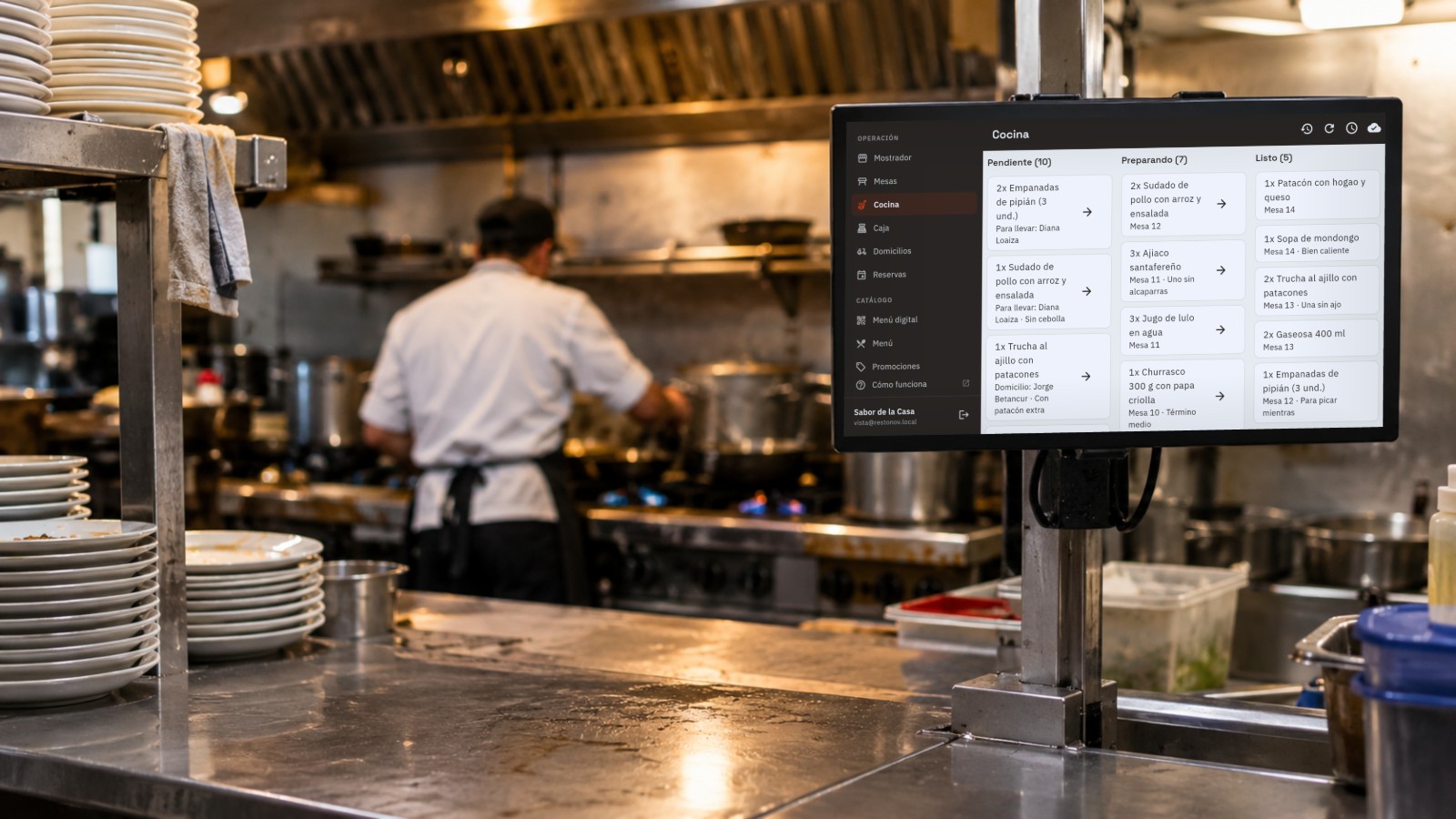 Monitor en el pase de una cocina mostrando la pantalla de cocina de Restonov, con los pedidos repartidos en pendientes, en preparación y listos.